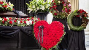 A display of flowers for funerals, with a large heart of roses placed before a casket